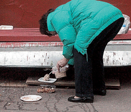 Приготовленную для животных еду женщина с любовью раскладывает на порции